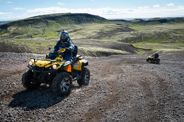Fjórhjólamaður ekur eftir malarslóða í hraunbreiðu