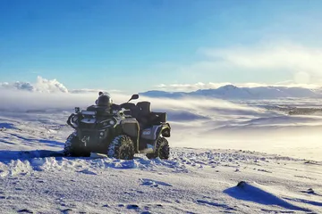 Fjórhjól stendur eitt á snævi þöktu hálendi