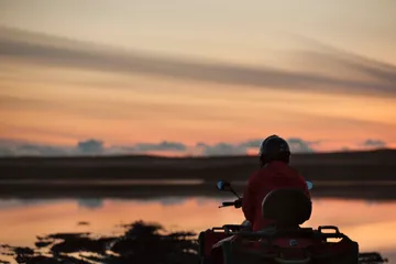 Fjórhjólamaður í silúettu við tjörn í kvöldroða